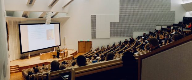 a man speaking in an auditorium with an audience