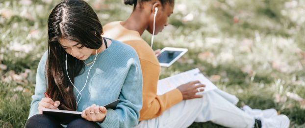 two college girls studying and listening to music in the forest